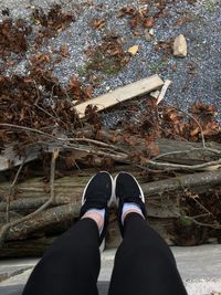 Low section of woman sitting by wood