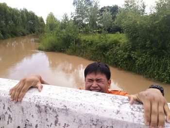 Man climbing retaining wall over river