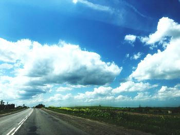 Road amidst field against sky