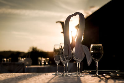 Close-up of wineglass on table against sky during sunset