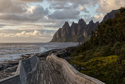 Scenic view of sea and dramatic mountain range against sky during sunset