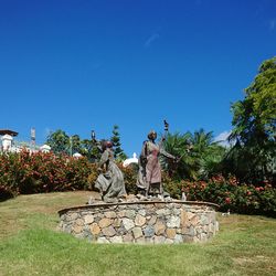 Statue by trees against clear blue sky