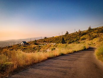 Road passing through landscape against clear blue sky