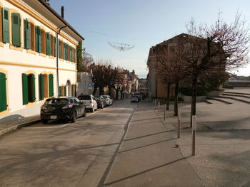 Cars on street by buildings in city against sky