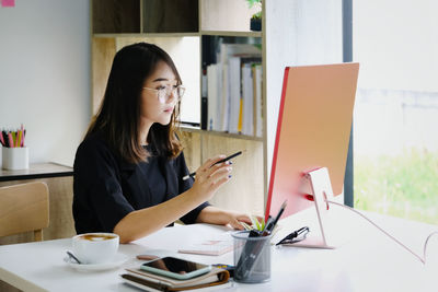 Woman using mobile phone while sitting on table