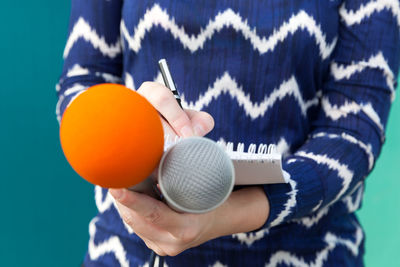 Midsection of female reporter holding microphone