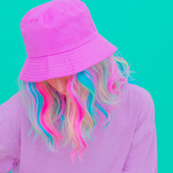 Close-up of woman wearing hat against colored background