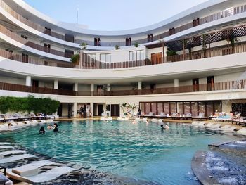 People in swimming pool against buildings in city