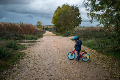 Rear view of boy riding bicycle on street