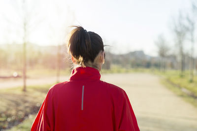 Rear view of mature woman running on road in park