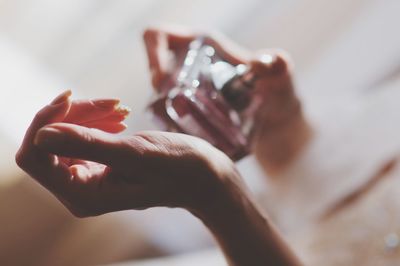 Cropped hands of woman applying perfume