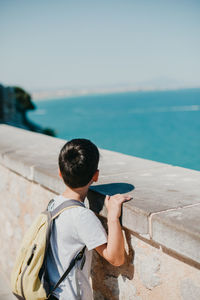 Rear view of man looking at sea against sky