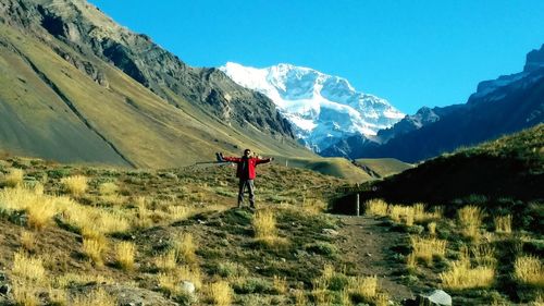 Man standing on field with arms outstretched against andes mountains during winter