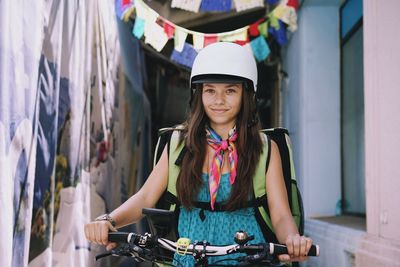 Portrait of smiling woman with bicycle on alley