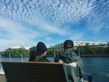 Rear view of people sitting on boat against sky