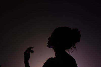 Silhouette woman looking away against colored background
