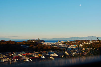Illuminated city by sea against clear sky