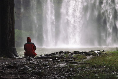 Rear view of person looking at waterfall