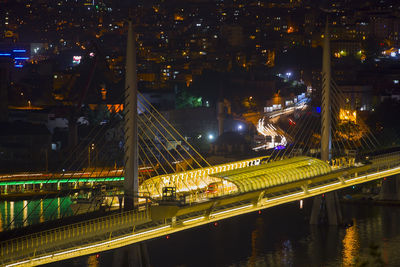 Illuminated railway bridge over river at night