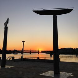 Silhouette built structure by sea against sky during sunset