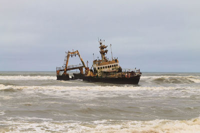 Fishing boat in sea against sky