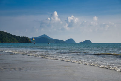 Waves of the azure andaman sea under the blue sky reaching the shores of cenang beach