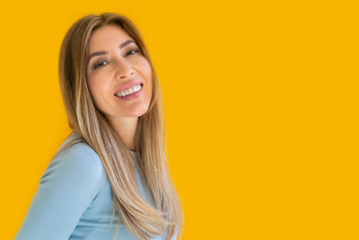 Portrait of young woman against yellow background