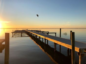 Pier over sea against sky during sunset