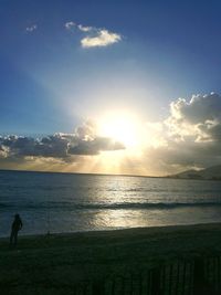 Silhouette man standing on beach against sky during sunset