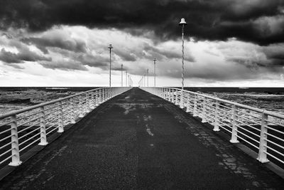 Empty bridge over sea against sky