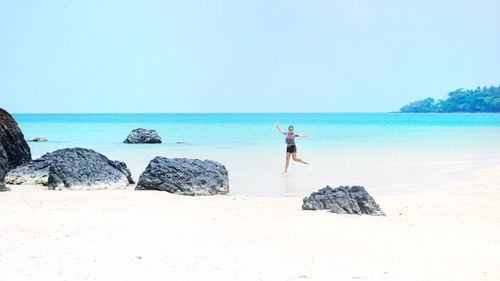 Woman enjoying on sea shore at beach against clear sky