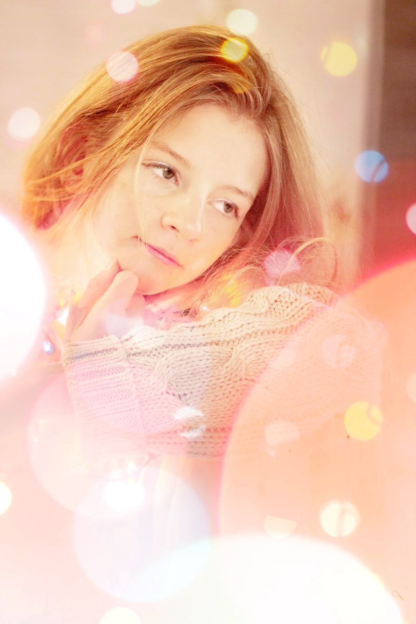 PORTRAIT OF A SMILING YOUNG WOMAN WITH ILLUMINATED HAIR