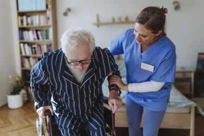 Smiling home caregiver assisting senior man at home