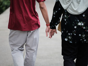 Midsection of couple holding hands