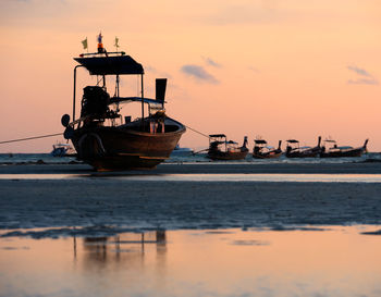 Boats in sea at sunset