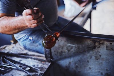 Midsection of man sculpting glass