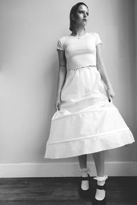 Young woman looking away while standing against wall