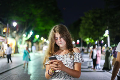 Young woman using mobile phone in city