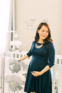 Portrait of smiling young woman standing against wall