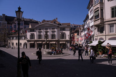 People on street against buildings in city