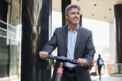 Mature businessman with e-scooter in the city