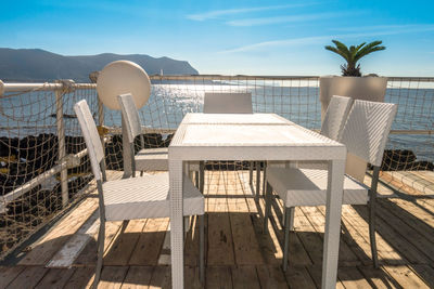 Chairs and table on beach against sky