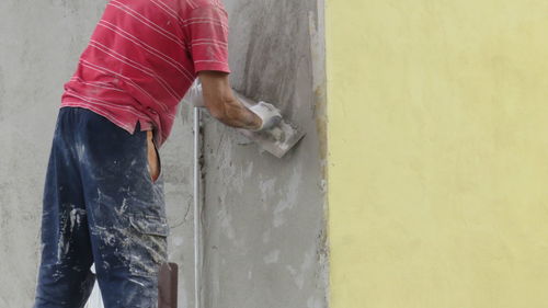 Midsection of worker plastering wall