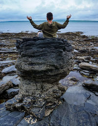 Full length of man on rock at beach against sky