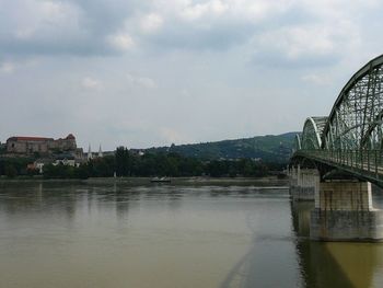 Bridge over river by buildings against sky