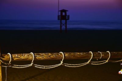 Close-up of rope against sea during sunset