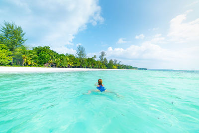 Rear view of man in swimming pool against sea