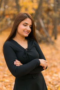 Portrait of young woman standing against trees