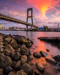 Bridge over river against sky during sunset