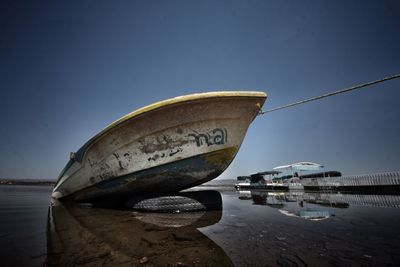 Close-up of boat moored on beach against clear sky